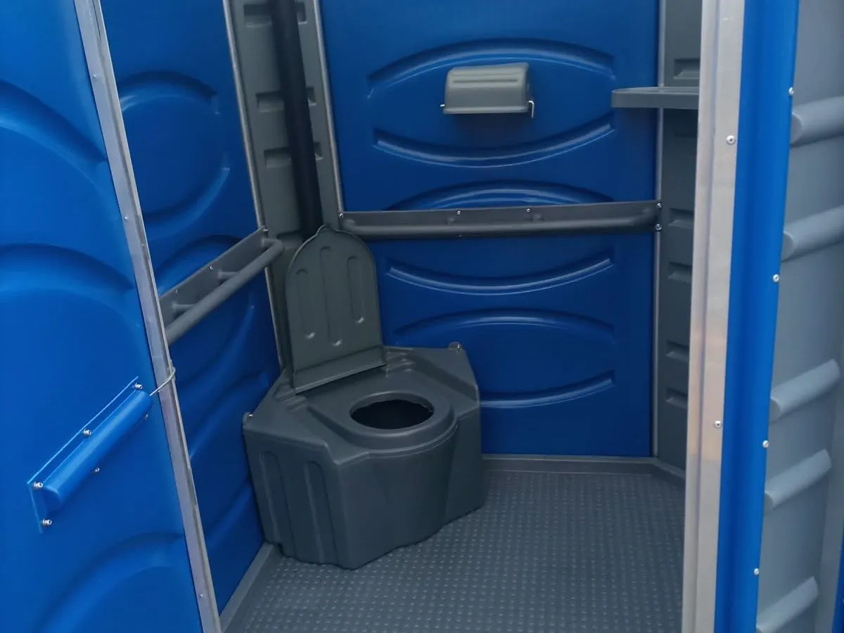 Interior de um banheiro químico da FR Renovar, com vaso, suporte de papel e barras de apoio